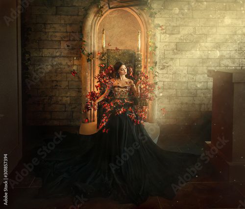 gothic dark queen sits in castle on golden throne. black dress with butterflies. Brick wall, large gothic room, magical sun rays from window. Long train fashionable silk skirt. Glamorous fantasy woman