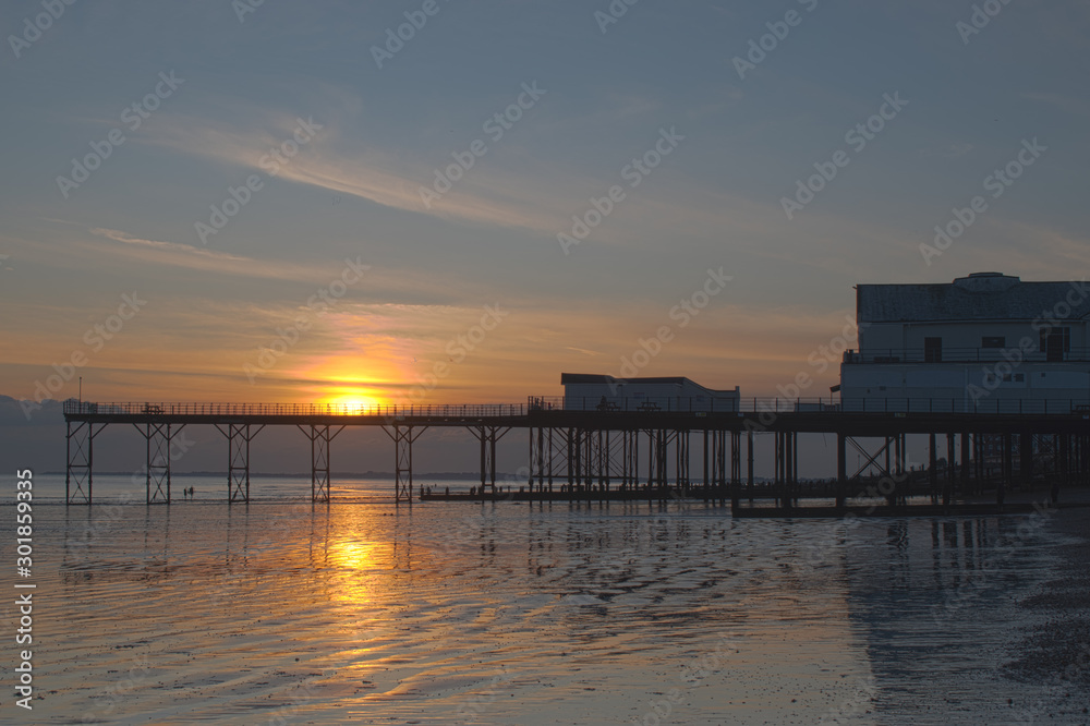 Beautiful sunset behind and reflections on the sand at low tide behind the Pier in Bognor Regis West Sussex.