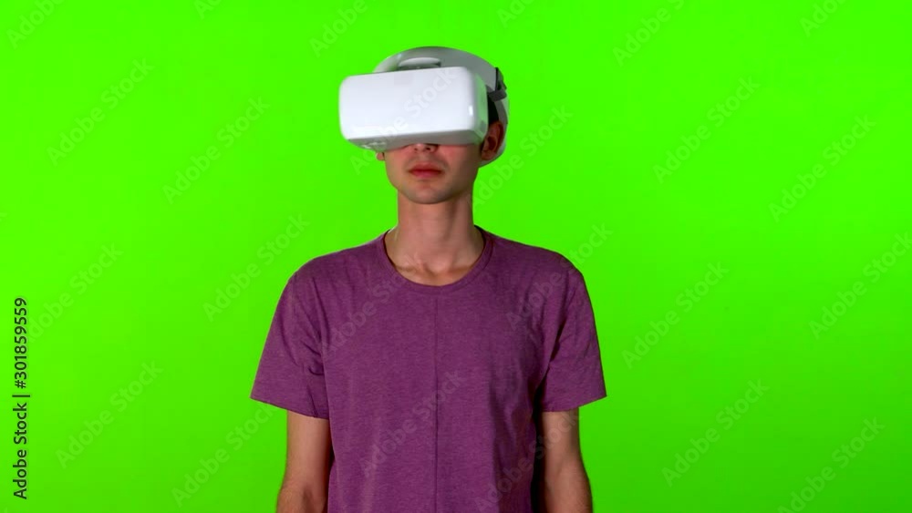Teenage boy using a VR application or game, looking around, medium shot over green screen. Teenage boy using a VR application or game, looking around, medium shot over green screen.