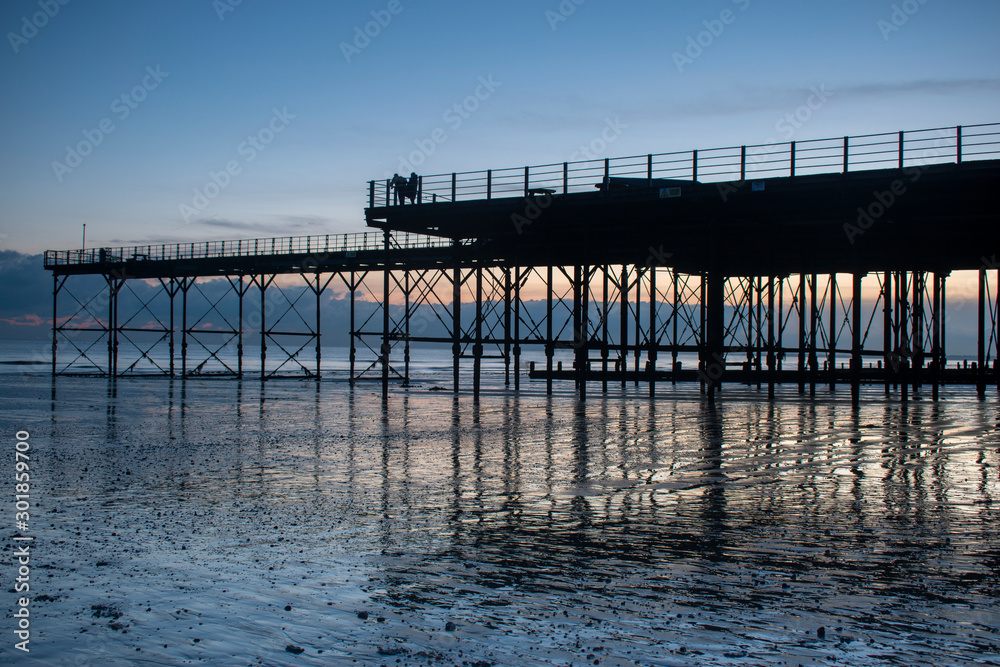 The Pier in Bognor Regis West Sussex with a beautiful sunset behind and reflections on the sand at low tide.