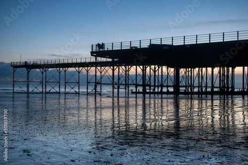 The Pier in Bognor Regis West Sussex with a beautiful sunset behind and reflections on the sand at low tide.