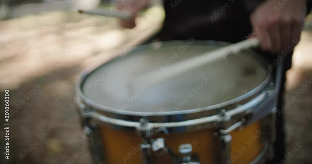 Shallow focus close up on drummer rhythm performance, drumming with drumsticks outdoors. Rack to push in focus. Shallow focus close up on drummer rhythm performance, drumming with drumsticks outdoors. Rack to push in focus.