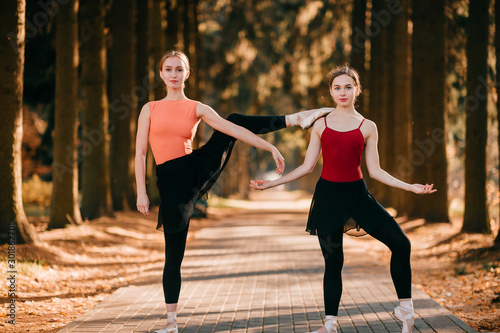Two elegant female ballet dancers standing in a funny pose and looking at camera with emotional face