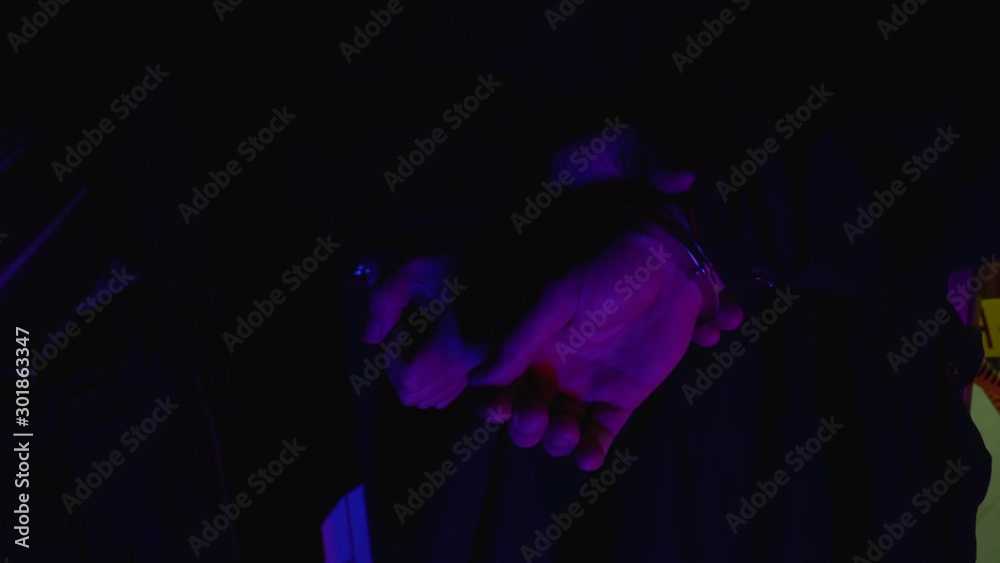 Policeman putting handcuffs on murderer, dead body lying on floor, bloody crime