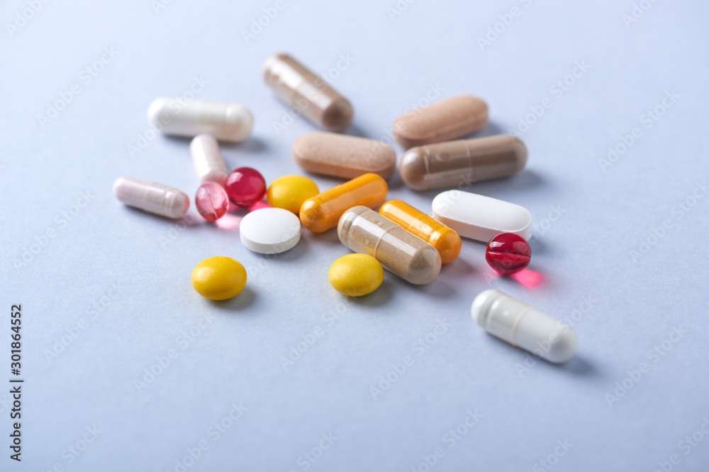 Multicolor vitamins and supplements on bright paper background. Concept for a healthy dietary supplementation. Close up. Multicolor vitamins and supplements on bright paper background. Concept for a healthy dietary supplementation. Close up.