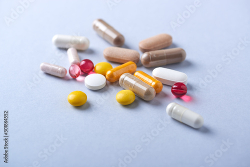 Multicolor vitamins and supplements on bright paper background. Concept for a healthy dietary supplementation. Close up.