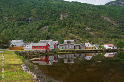 Old wooden houses with reflection at the pond, foot of the mountain in Laerdal, Norway