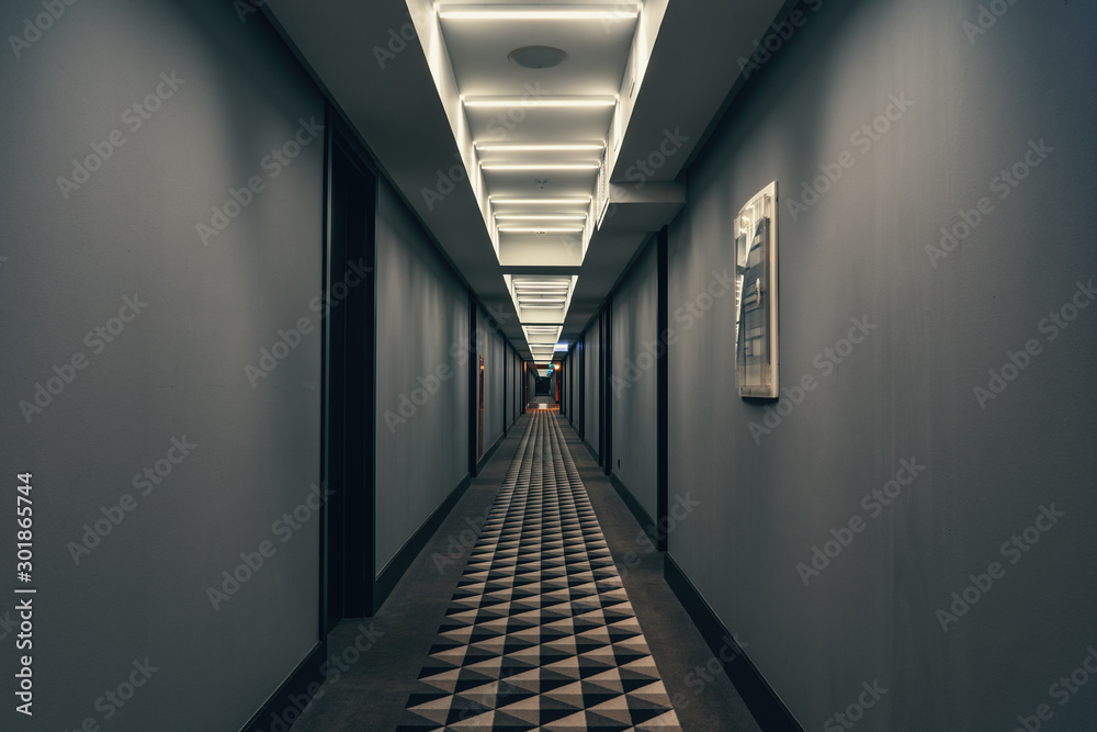 Dark corridor with illumination on ceiling. Tunnel view of empty hotel corridor in night time, toned - obrazy, fototapety, plakaty 