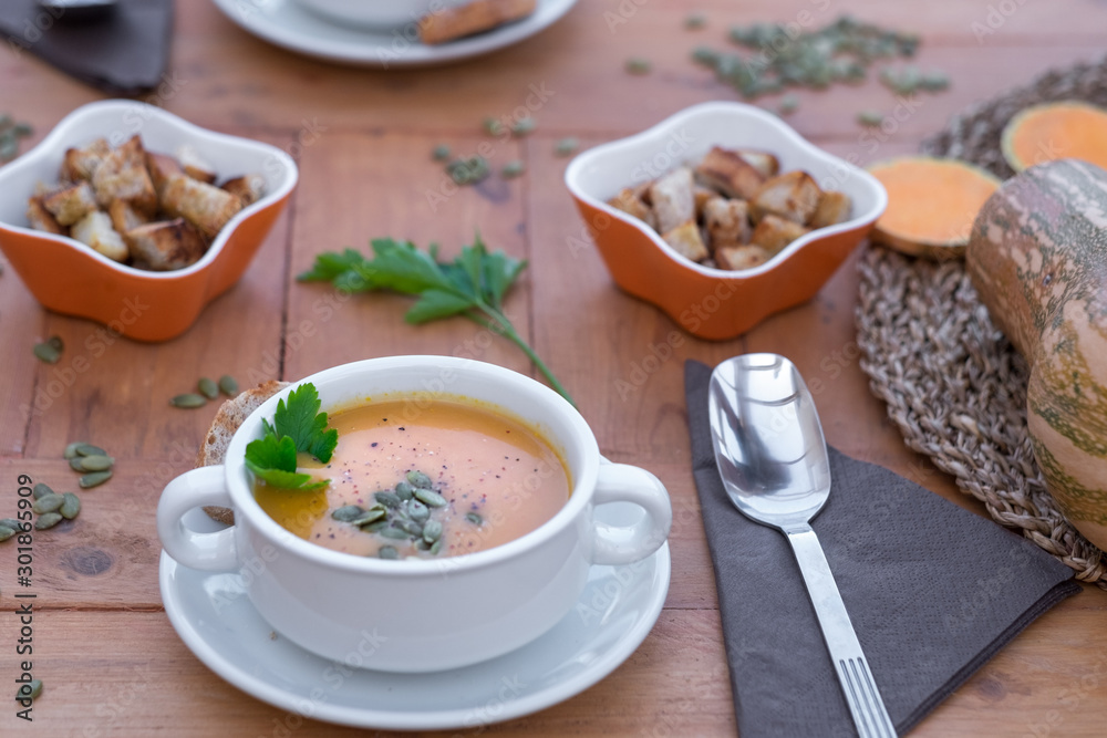 Autumn winter time. Wooden table with two bowls of pumpkin cream soup. In the middle of the table bread croutons.