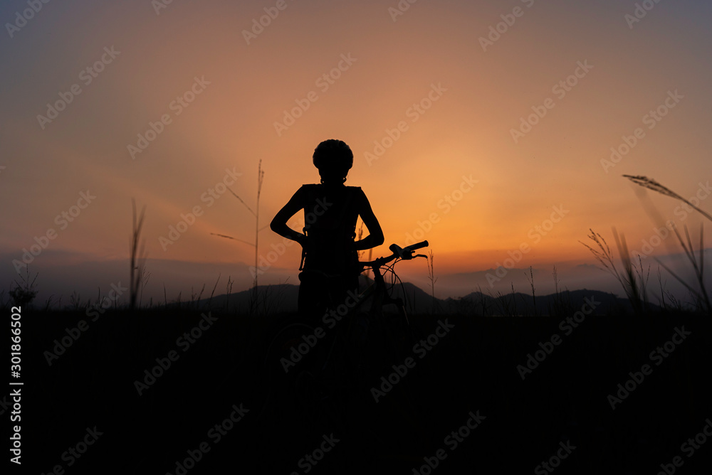 Obraz premium A woman riding a bicycle silhouette At the sunsets, relax at the end of the day