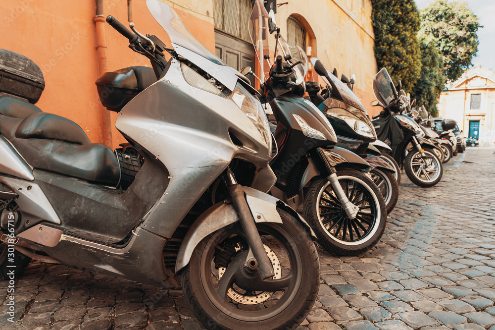 Many motor scooters parked on old Rome street, Italy .