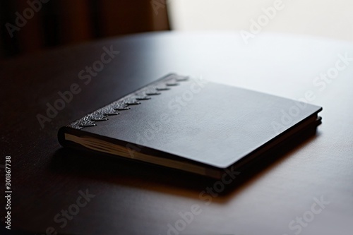 Bilde på lerret Note book with hard wooden cover on table by the window in natural light