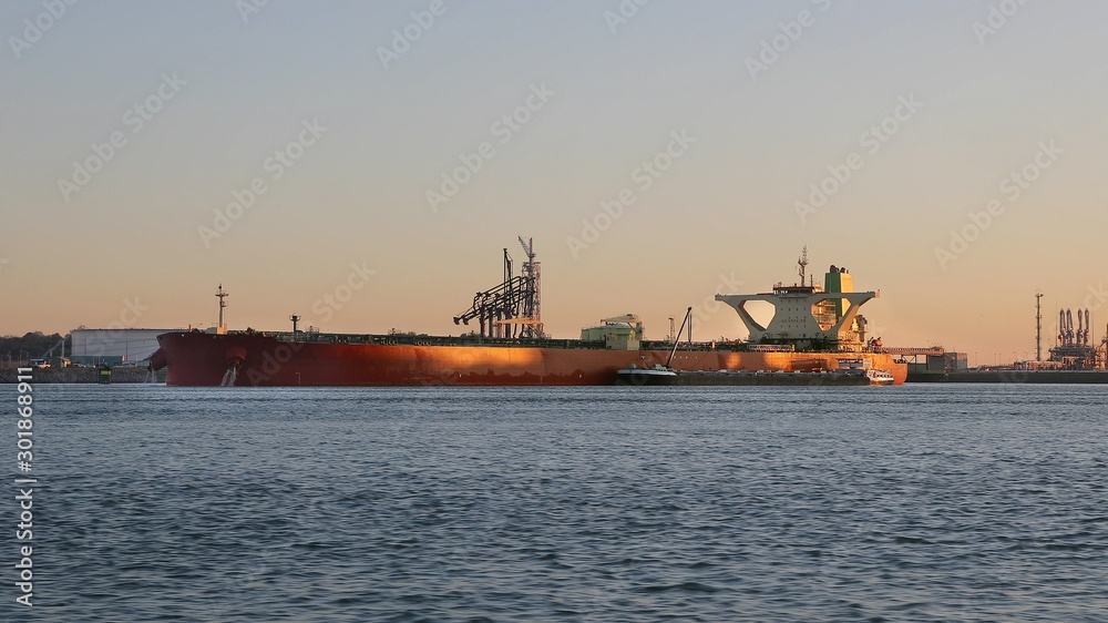 Huge oil tanker ship docket in the Port of Rotterdam, pumping out ballast water