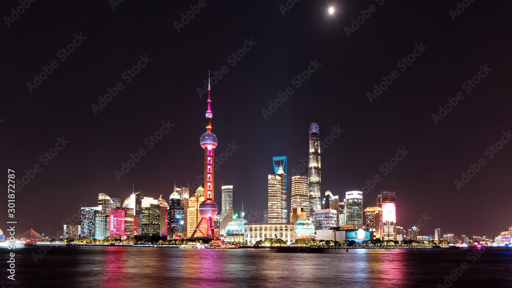 Skyline view from Bund waterfront at night with moon on dark blue sky background, Lujiazui is the business quarter of Shanghai, beautiful shanghai night cityscape.