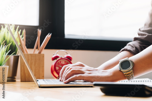 Close up of businessman or accountant hand holding pen working on laptop computer for calculate business data, accountancy document and calculator at office, business concept