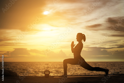 woman practicing yoga during surrealistic sunset at the seaside. healthy concept and workout.