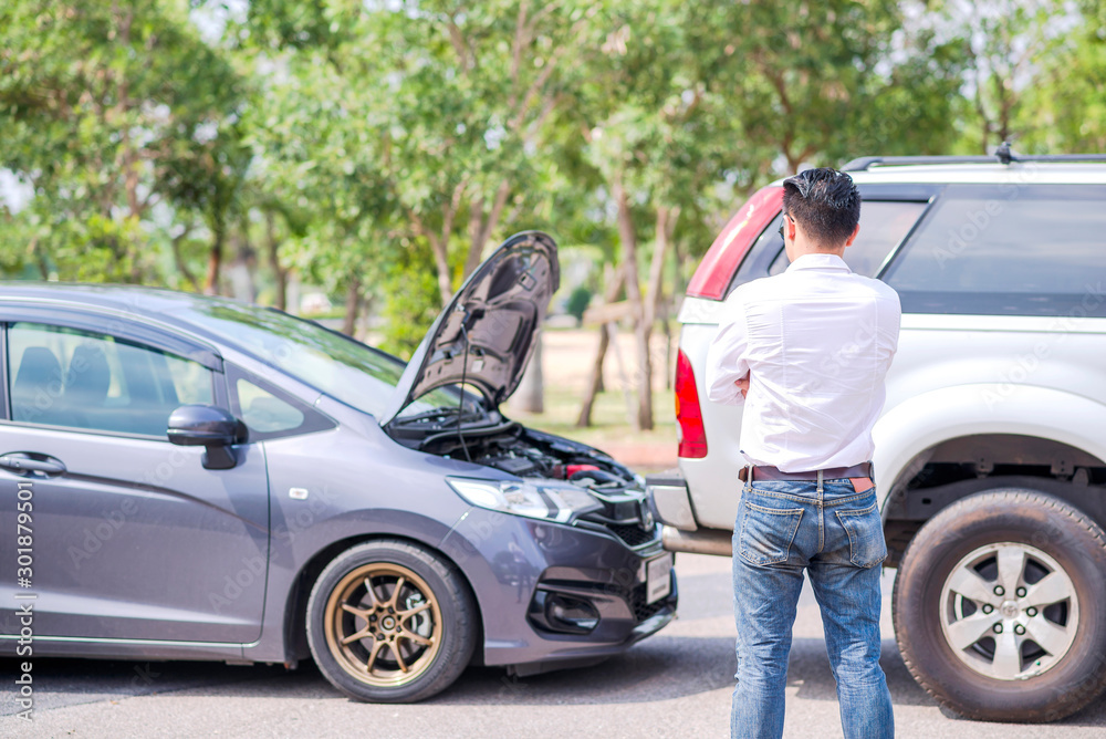 The driver is calling for insurance after a traffic accident. car crash accident on street, damaged automobiles after collision. The car crashed on a road between a saloon and a pickup. The driver is calling for insurance after a traffic accident. car crash accident on street, damaged automobiles after collision. The car crashed on a road between a saloon and a pickup.