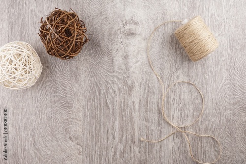 twine and two decorative balls, burlap and coffee mug on light gray wooden background.