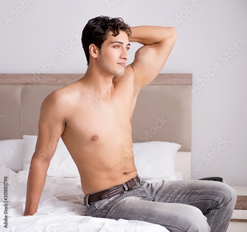 Young handsome shirtless guy showing nude torso sexy on bed at h