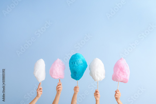 Female hands with different cotton candy on light background