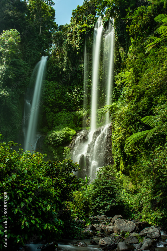 Twin waterfalls crashing down the cliff in lush tropical jungle vegetation Twin waterfalls crashing down the cliff in lush tropical jungle vegetation