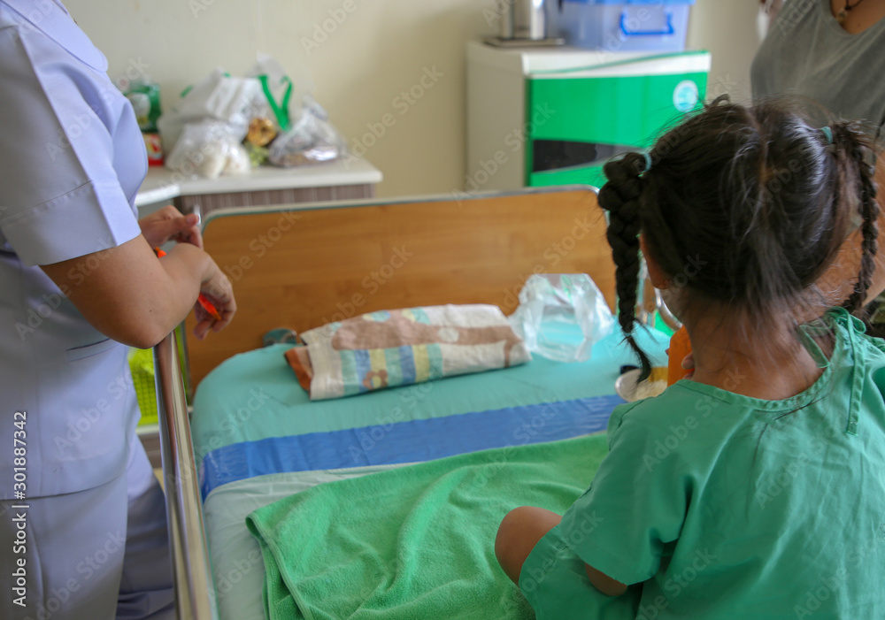 Sick child with sickness on the bed in the hospital with nurse and her mother. Sick child with sickness on the bed in the hospital with nurse and her mother.