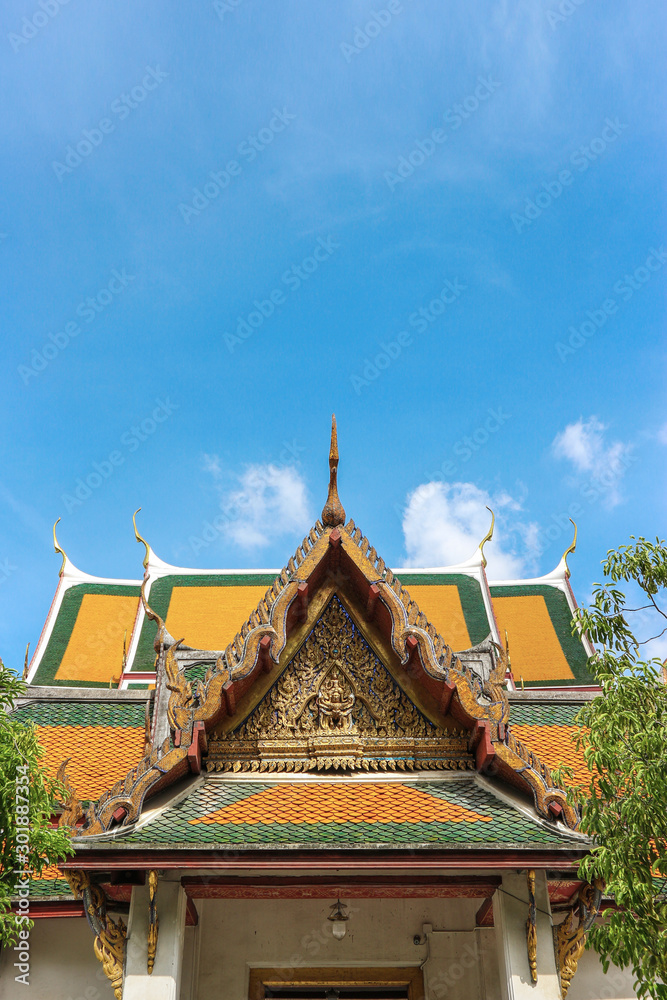 Top part of Thai temple roof with blue sky background.