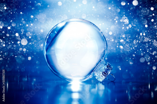 Clear glass Christmas ornament on blue glittering lights background with blank empty space