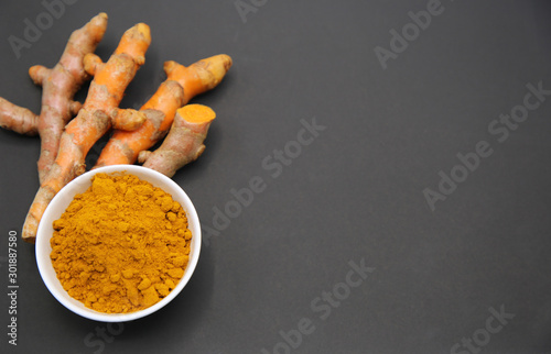 fresh root organic turmeric and powder on black background.