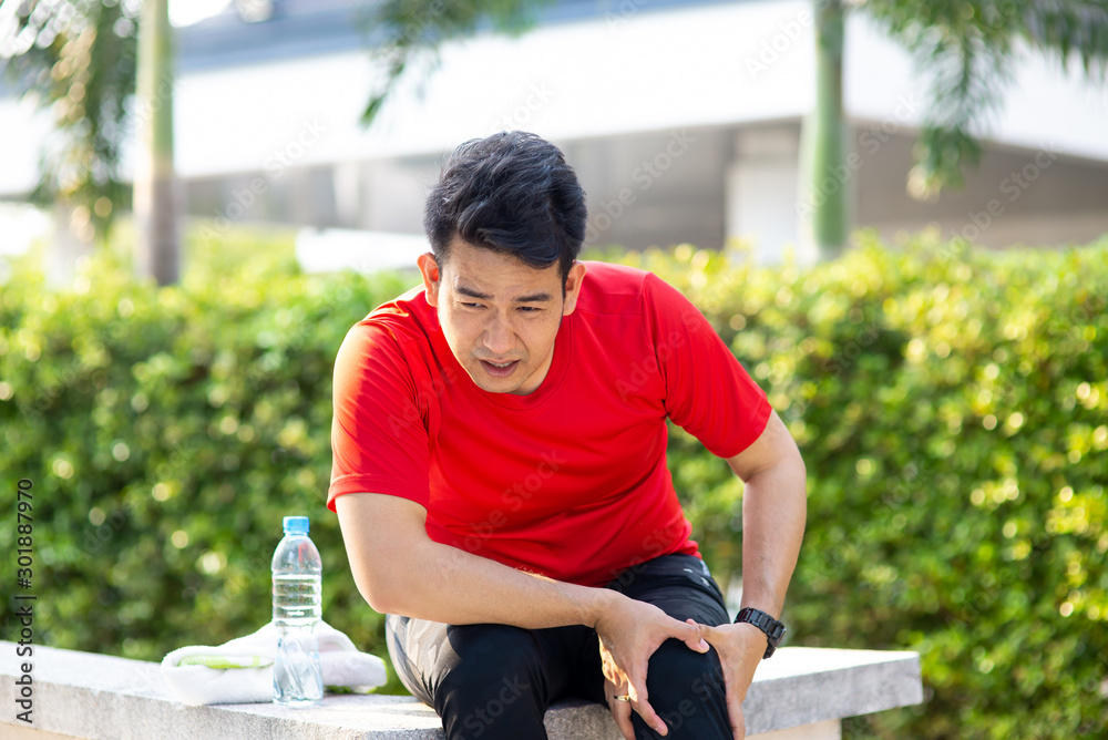 Asian sport man in red t-shirt hurts his leg with accident.