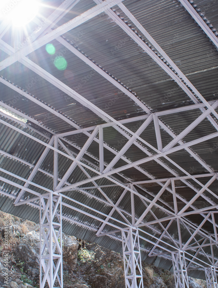 Fototapeta premium Low angle shot of a tin shed with iron frames and beautiful sun flares from top