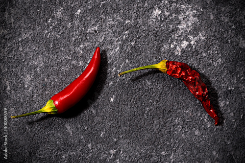 Top view of red fresh and dried small chili peppers on black stone background. the concept of penis, potency and impotence, drugs for potency
