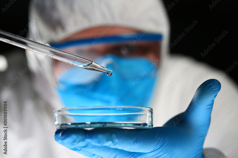 Male chemist look at microscope hold test tube Male chemist look at microscope hold test tube