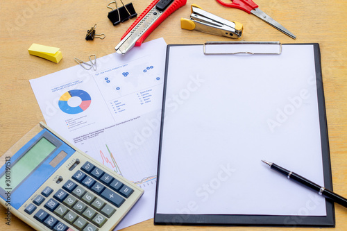 Businessman working on a laptop at office desk with paperwork and other objects around, top view