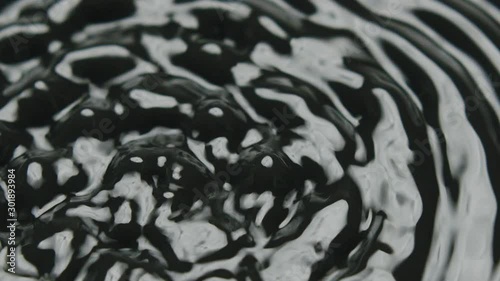 Calm water starts to vibrate and forming cymatic patterns. Static loopable shot.