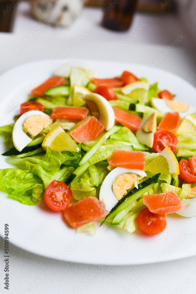 vegetable salad on a white plate. Fresh salad with egg, tomatoes, spinach and avocado on a white wooden background top view. Healthy food.