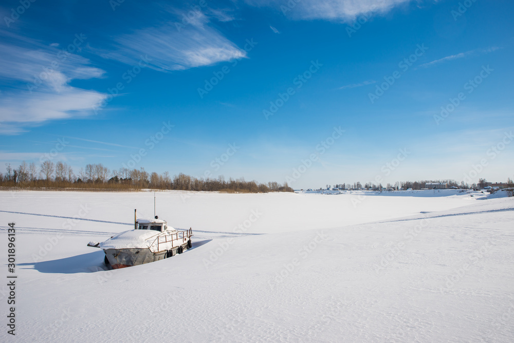 Ship in the snow. Coast of the frozen river. Winter landscape.