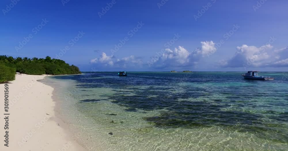 Fishing boats anchored on calm bay of tropical island with a wide sandy beach on a cloudy morning in Maldives Fishing boats anchored on calm bay of tropical island with a wide sandy beach on a cloudy morning in Maldives