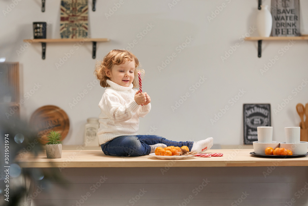 Cute Baby in the kitchen. Christmas or New Year. With tangerines.