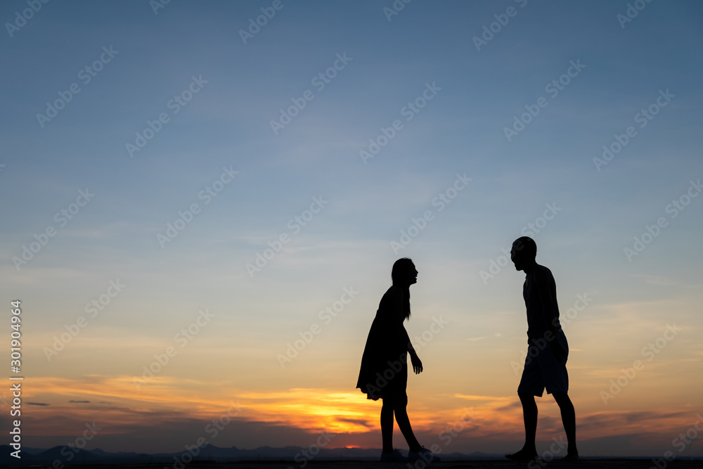 Silhouettes of happy young couple against the sunset sky.