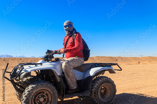 Young man in safari trip through egyptian desert driving ATV. Quad bikes safari in the desert near Hurghada, Egypt © olyasolodenko