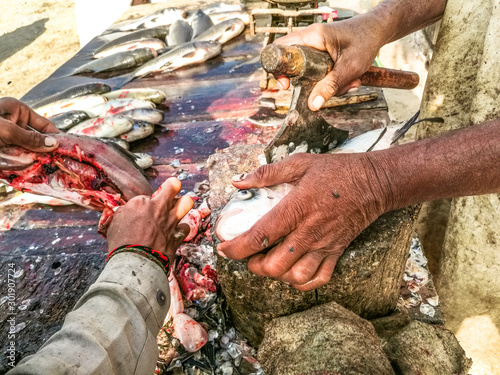 a fisherman is cutting fresh and healthy fishes at his stall in the local market in Pakistan 