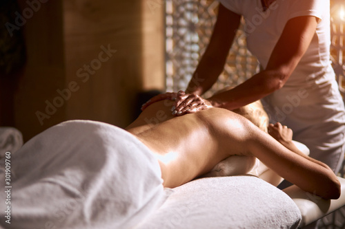 Professional female masseur doing deep shoulder massage in wellness beauty spa, woman lying on massage table under white towel, total relaxation concept, close up, indoor shot