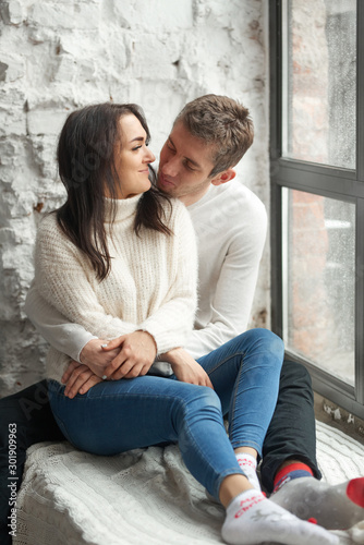Loving couple on a light background on the windowsill. Love, cares, warmth.