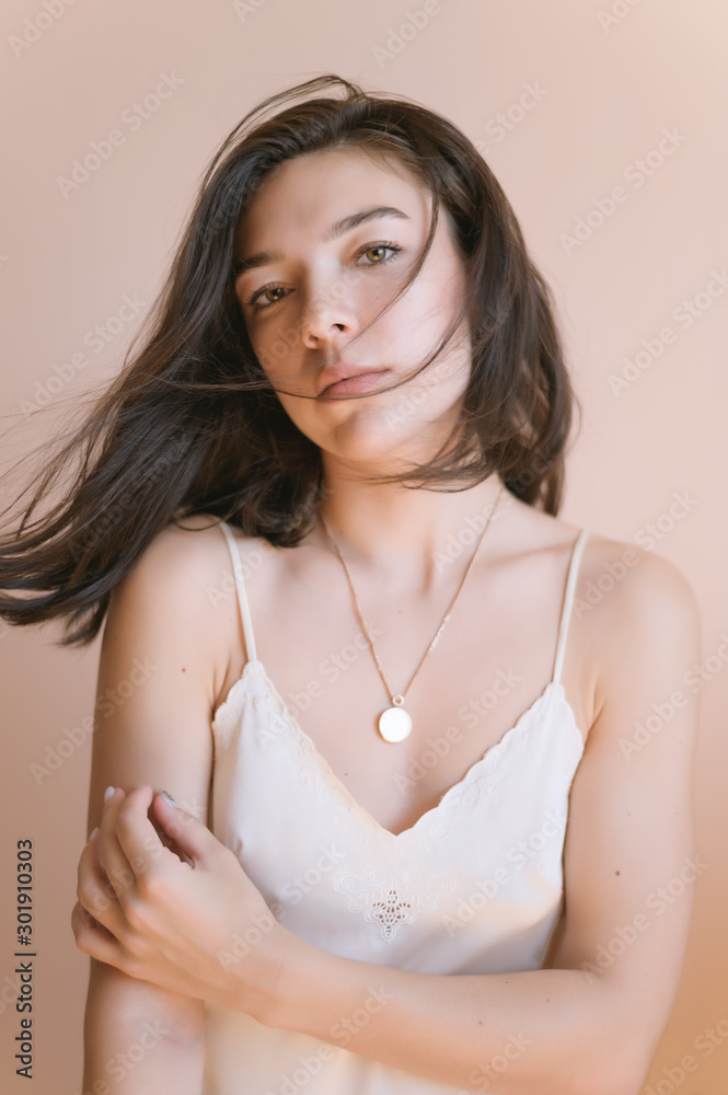 Beautiful young woman posing on beige wall background.