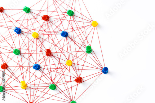 Network with colorful pins and string   linked together with string on a white background suggesting a network of connections.