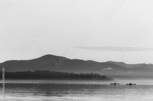 Beautiful view of a lake with two distant men on canoes © Massimo