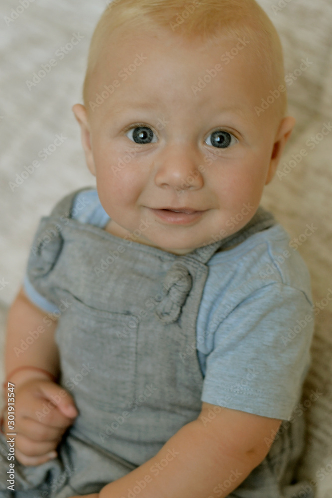 The four month old baby sits on the couch and smiles The four month old baby sits on the couch and smiles