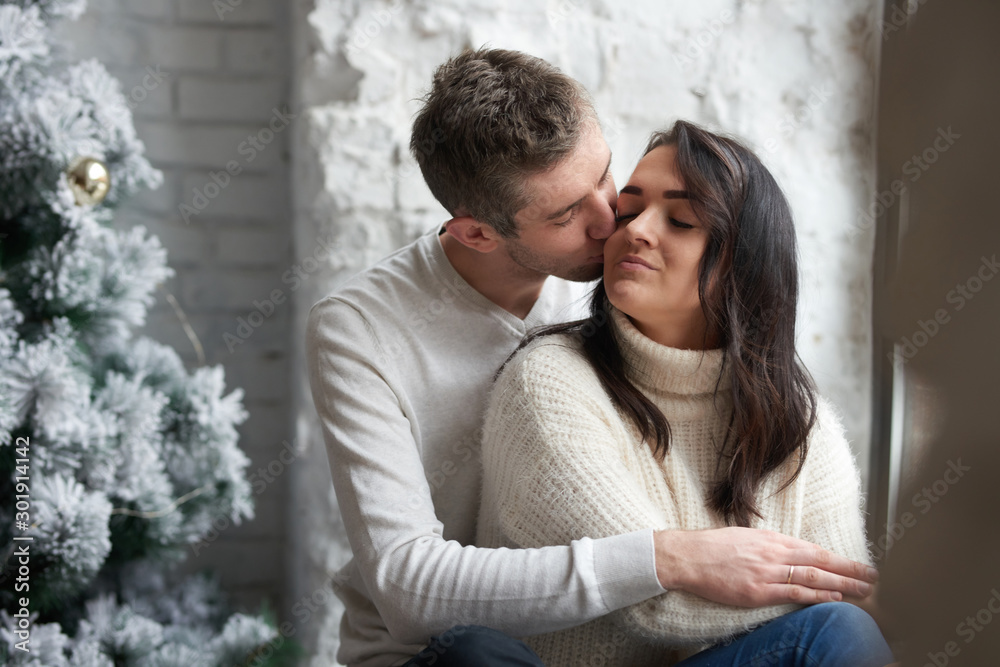 Loving couple on a light background celebrates Christmas. Love, cares, warmth.