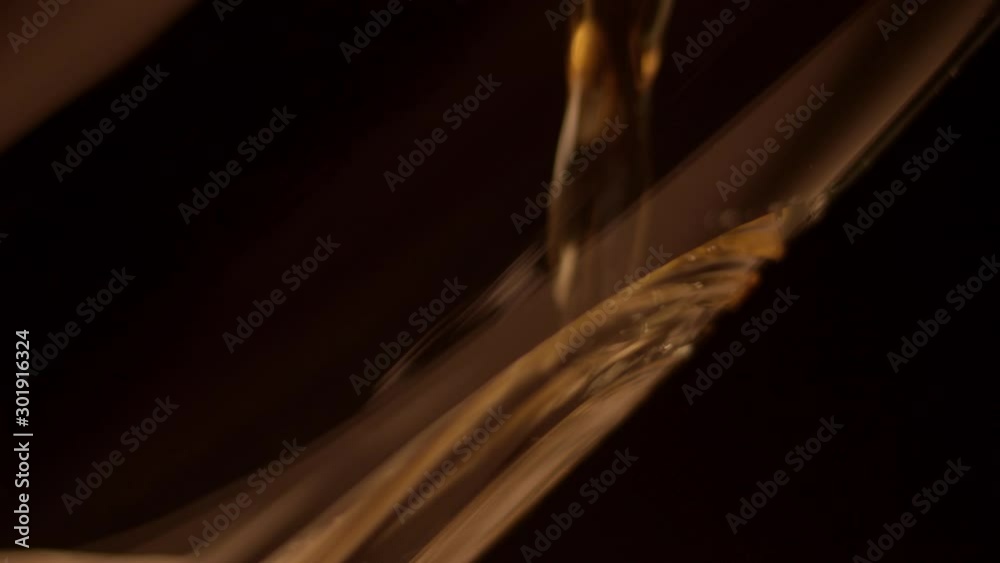 Beer poured against inside of glass in dark room, extreme close-up Beer poured against inside of glass in dark room, extreme close-up